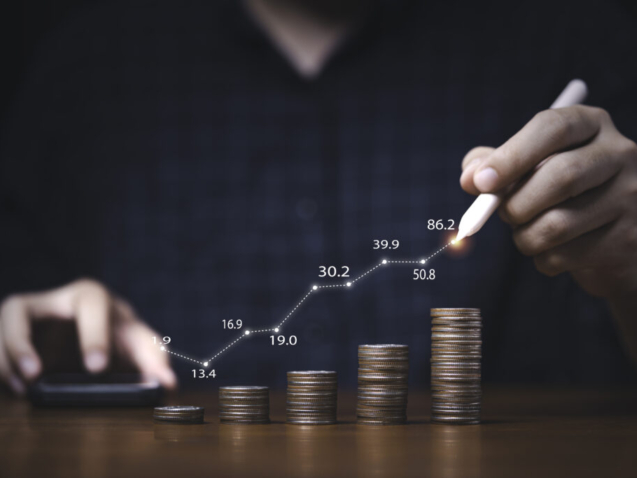 Trader writing increasing graph on coins stacking for investment profit growth and saving concept.