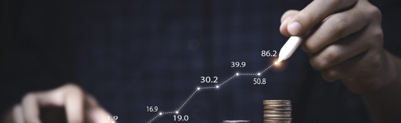 Trader writing increasing graph on coins stacking for investment profit growth and saving concept.